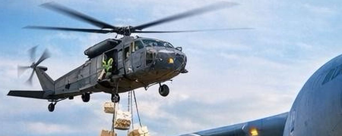 Black Hawk helicopter sling-loading palletized cargo alongside a C-17