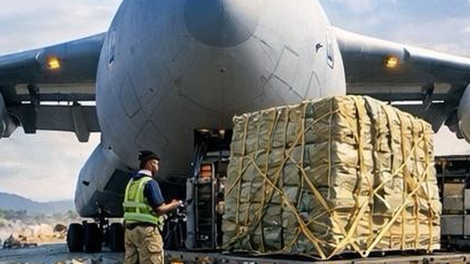 C-17 with palletized cargo and ground crew at an austere airfield